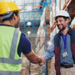 Men shaking hands in a warehouse showing a vendor managed inventory strategic partnership