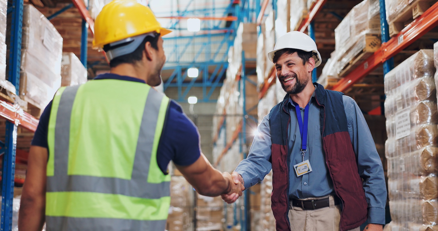 Men shaking hands in a warehouse showing a vendor managed inventory strategic partnership