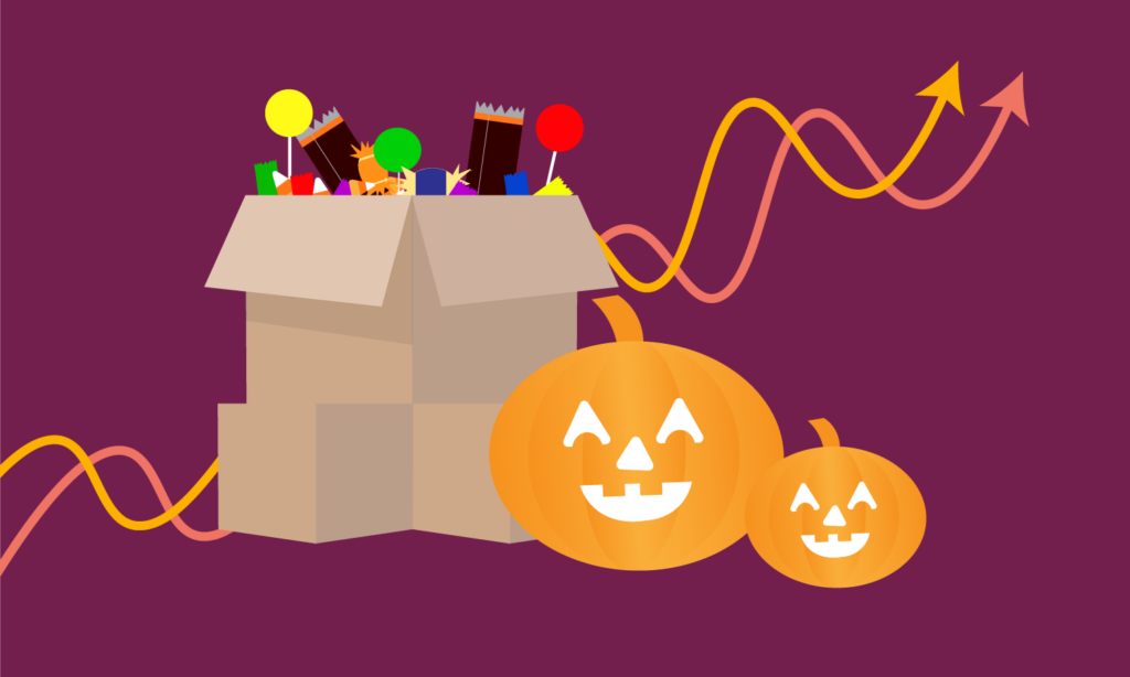 box of halloween candy beside two jack-o-lanterns